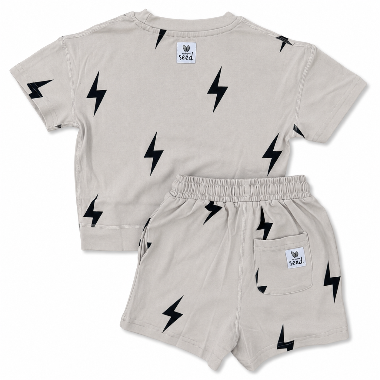 A toddler's two-piece clothing set consisting of a short-sleeve t-shirt and matching shorts in a light beige color, both printed with a black lightning bolt pattern. The set is displayed flat against a clean white background, showing both the front and back views.