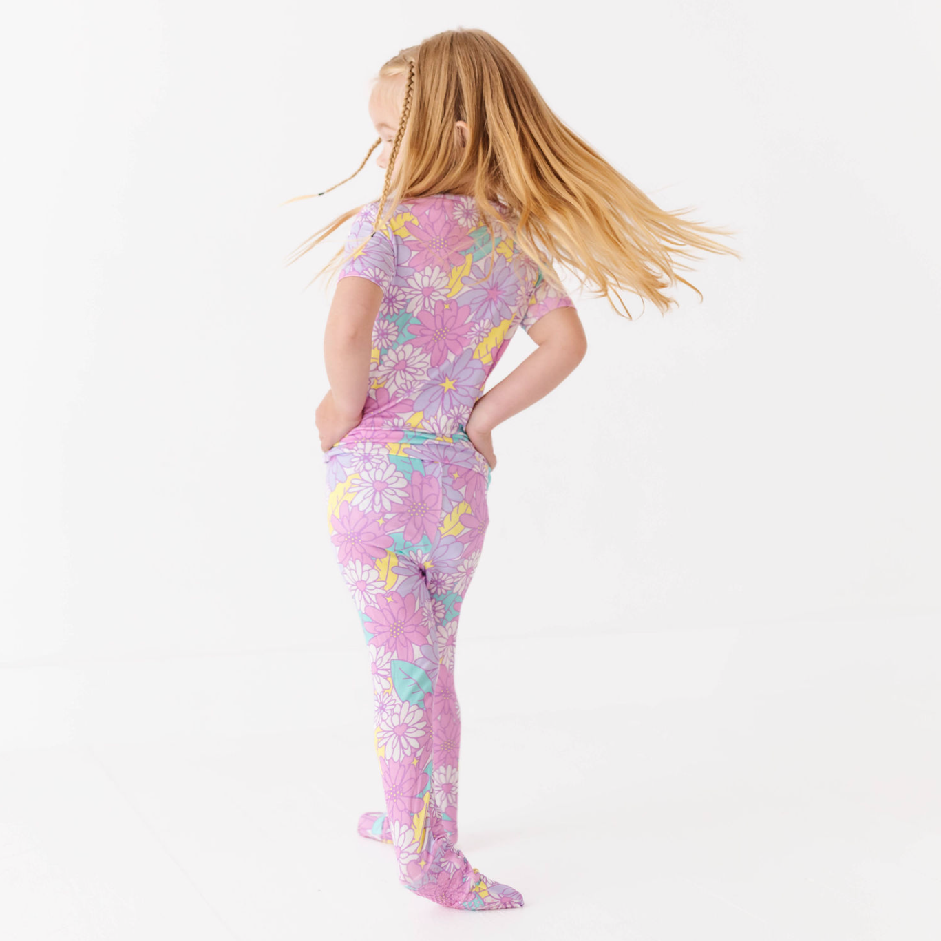 Child wearing a pink floral onesie on a white background