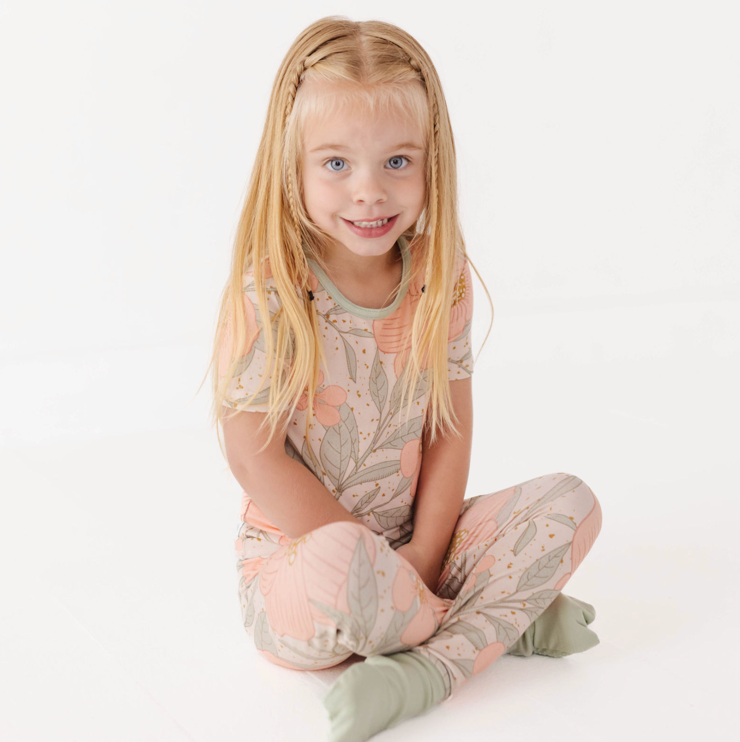 Young girl wearing a floral pajama set on a white background