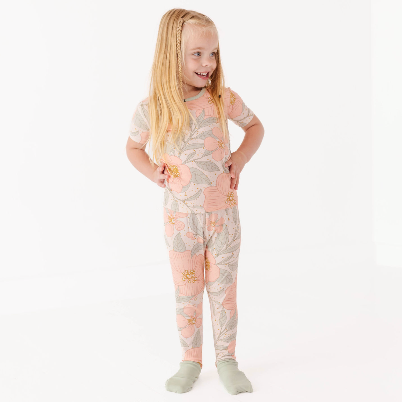 Young girl wearing a floral patterned onesie on a white background