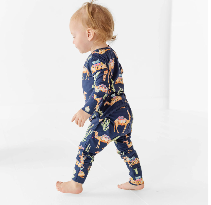 Child wearing a navy blue onesie with camel print on a white background