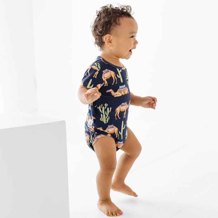 Baby wearing a navy blue onesie with animal print on a white background