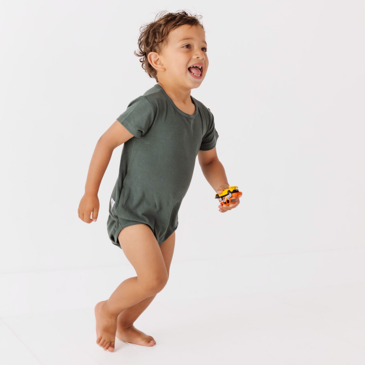 Child wearing a green onesie on a white background