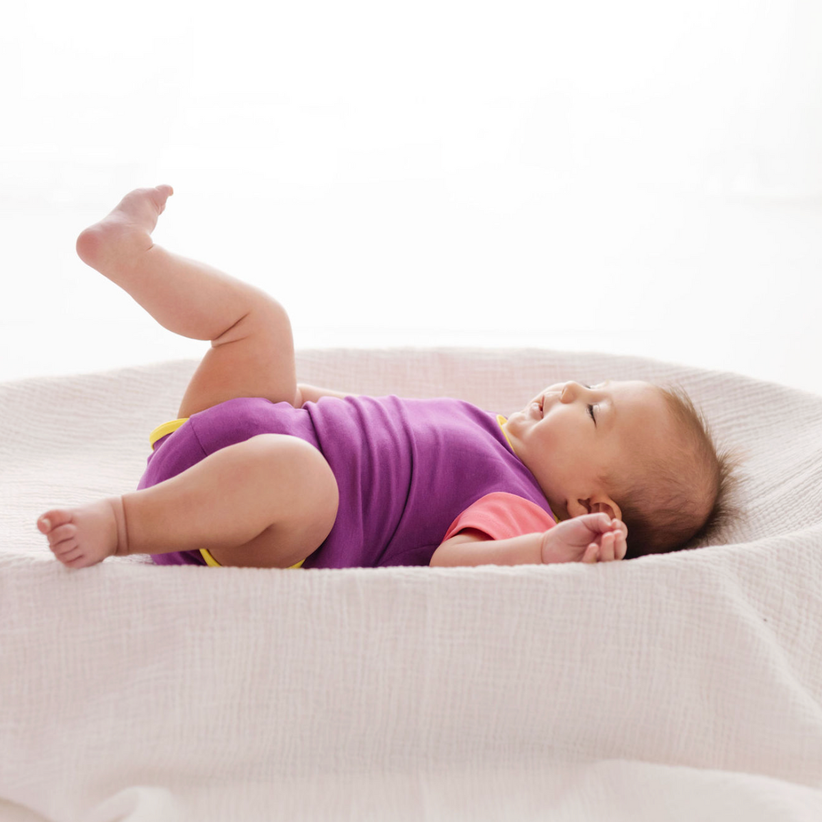 Baby lying on a white blanket with a white background
