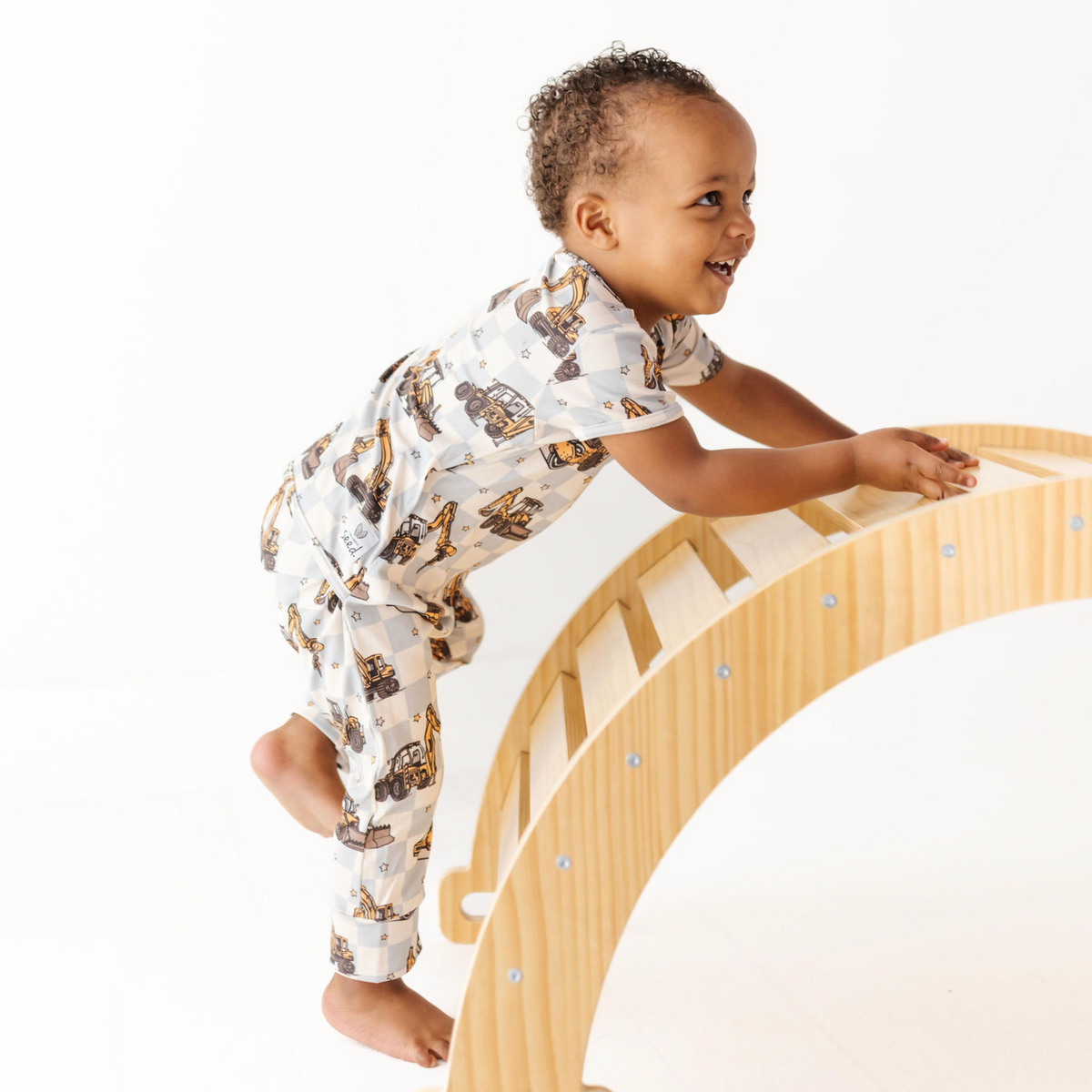 Child playing on a wooden climbing toy with a white background