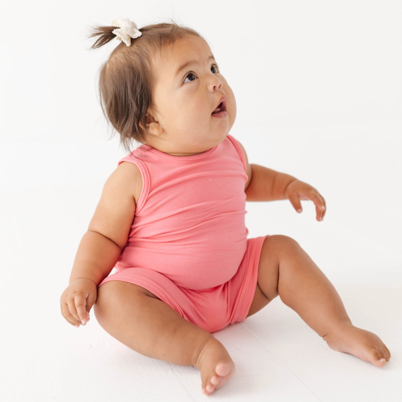 Baby in a pink outfit sitting on a white background