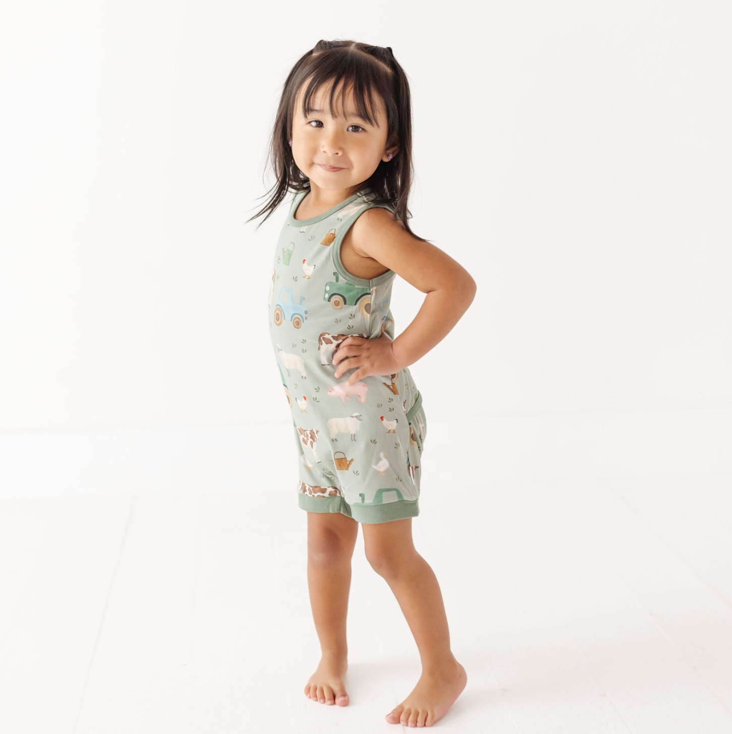 Child wearing a light green sleeveless top and shorts with animal prints on a white background