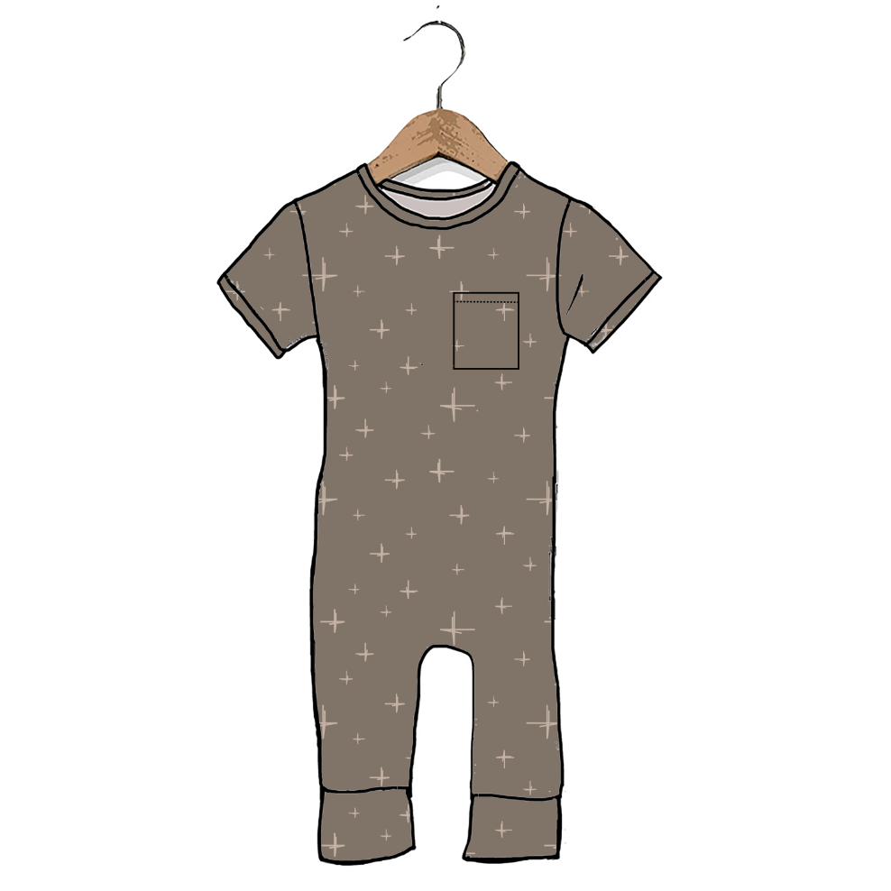 A short-sleeve baby jumpsuit or romper in taupe with a small chest pocket and scattered white plus-sign pattern, shown hanging on a wooden hanger against a plain white background.