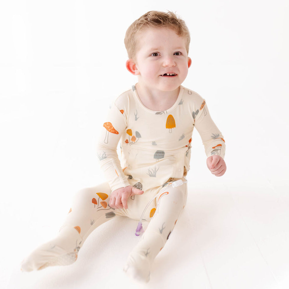 Baby wearing a patterned onesie sitting on a white surface
