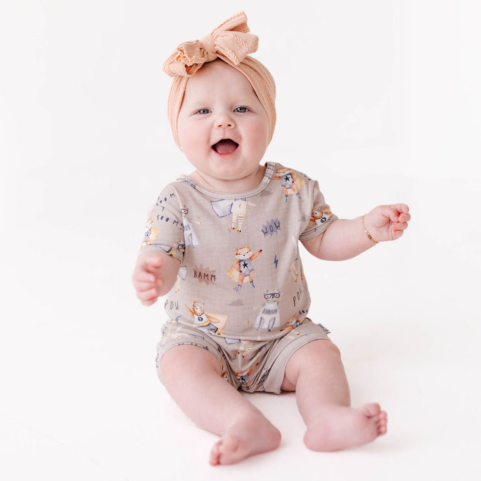 Baby wearing a patterned onesie and headband on a white background