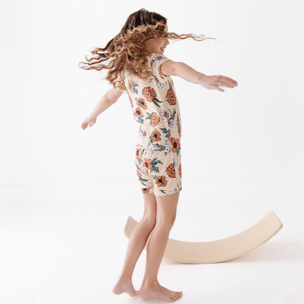 Child in a floral dress standing on a white background