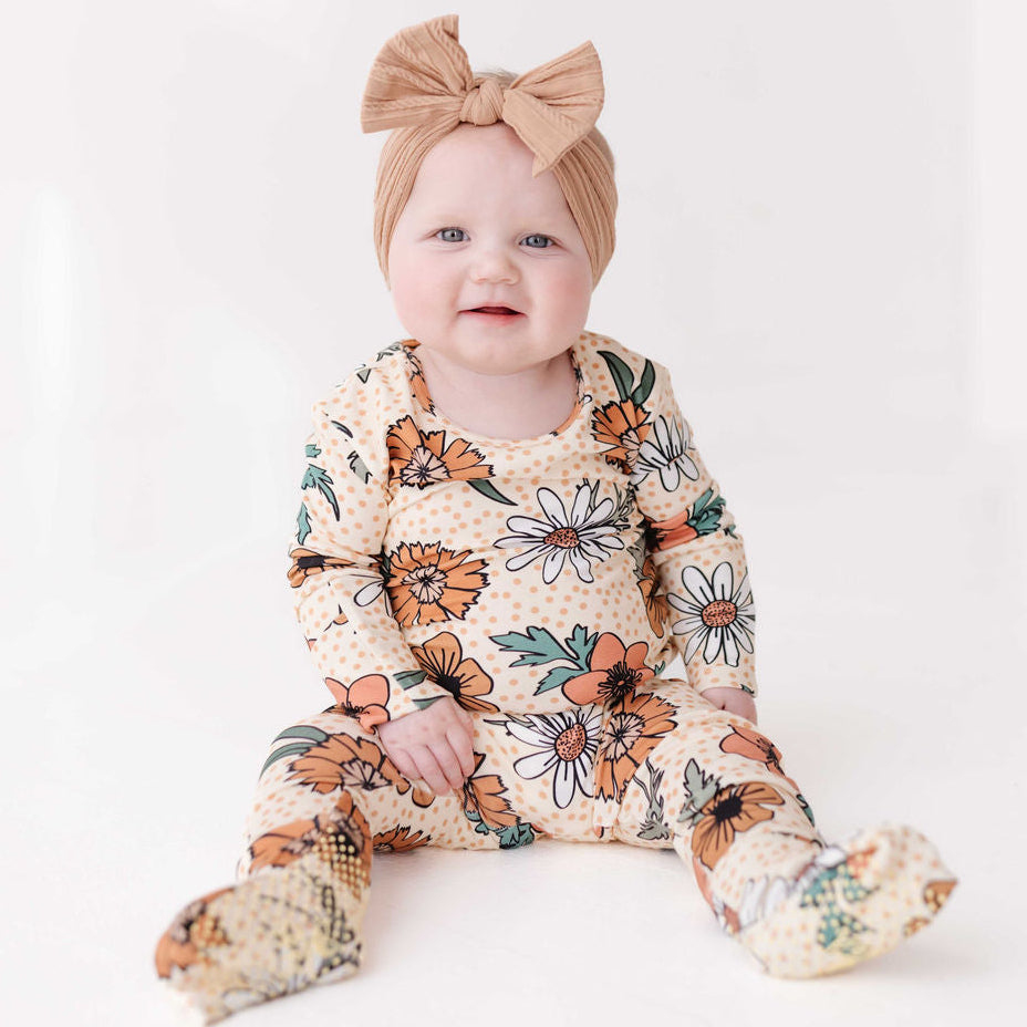 Baby wearing a floral onesie and headband on a white background