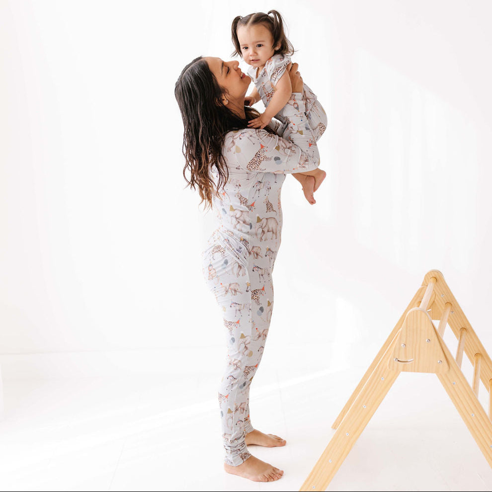 Woman and child in matching pajamas with a wooden play structure in the background