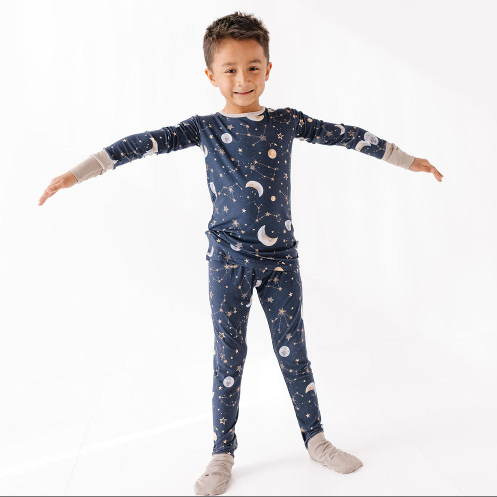 Child wearing a navy blue pajama set with celestial pattern on a white background