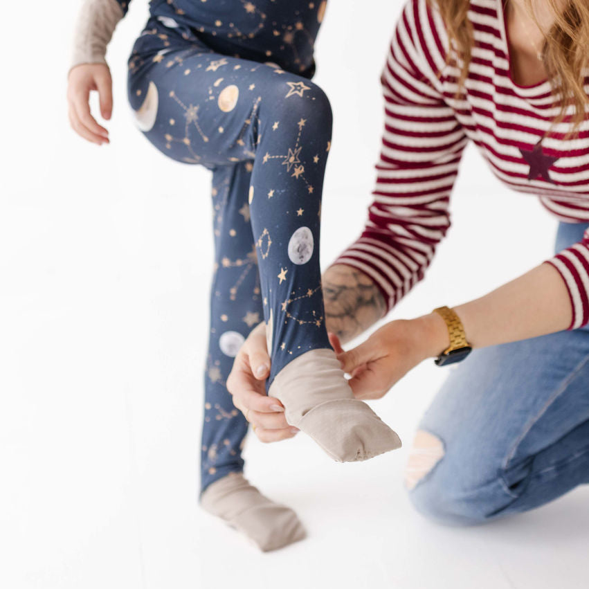 Person helping a child put on socks with a white background