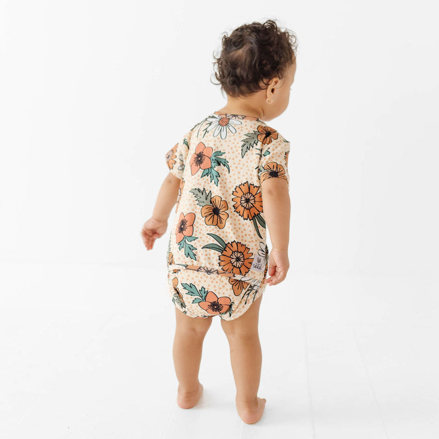 Baby wearing a floral romper on a white background