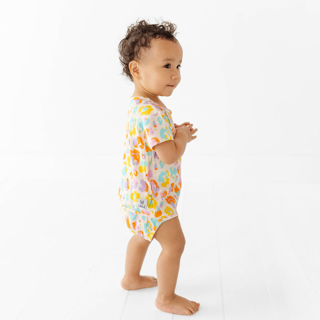 Baby wearing a colorful onesie on a white background