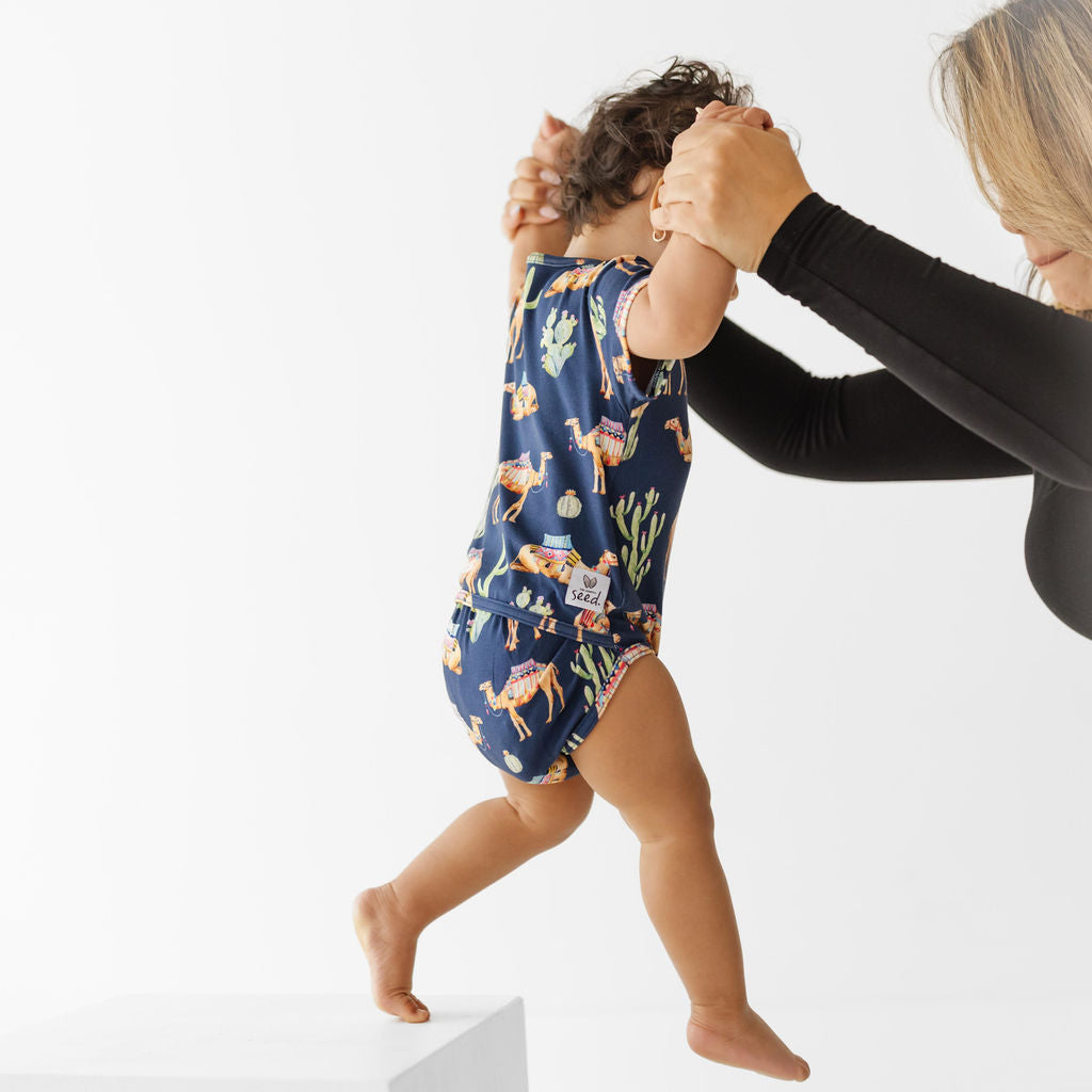 Woman helping a child learn to walk on a white background