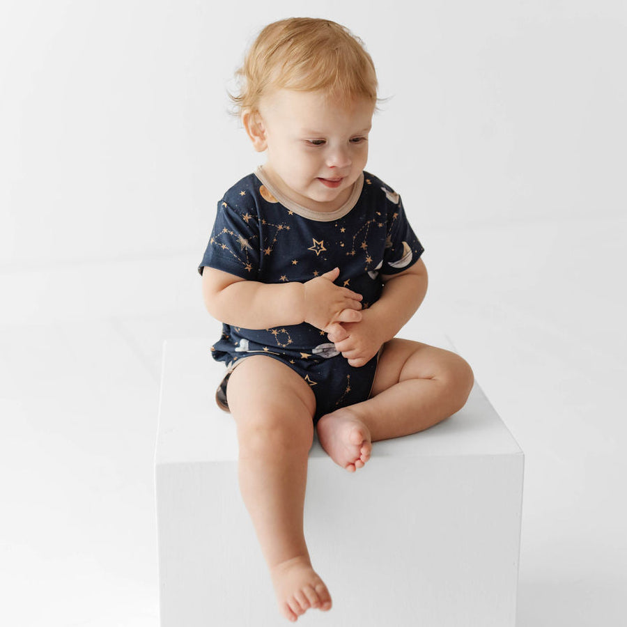 Child sitting on a white block against a plain background