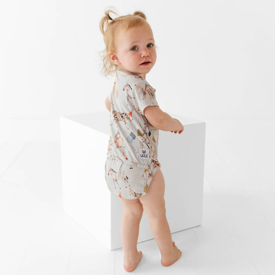 Baby wearing a patterned onesie standing against a white background