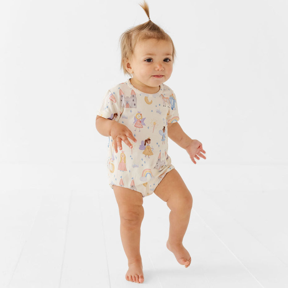 Baby in a patterned onesie standing on a white background