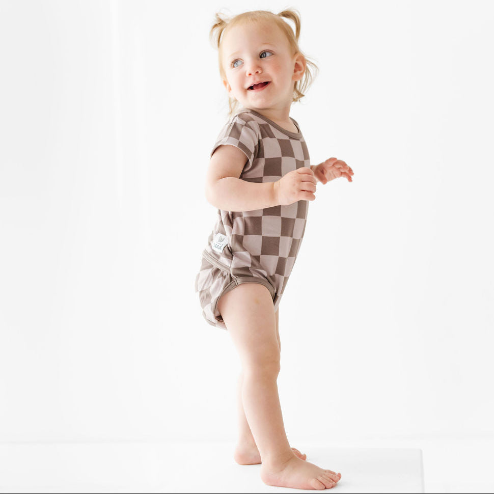 Child wearing a checkered romper on a white background