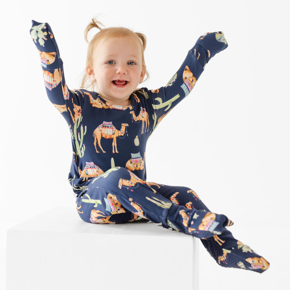Child wearing a navy blue pajama set with animal prints on a white background