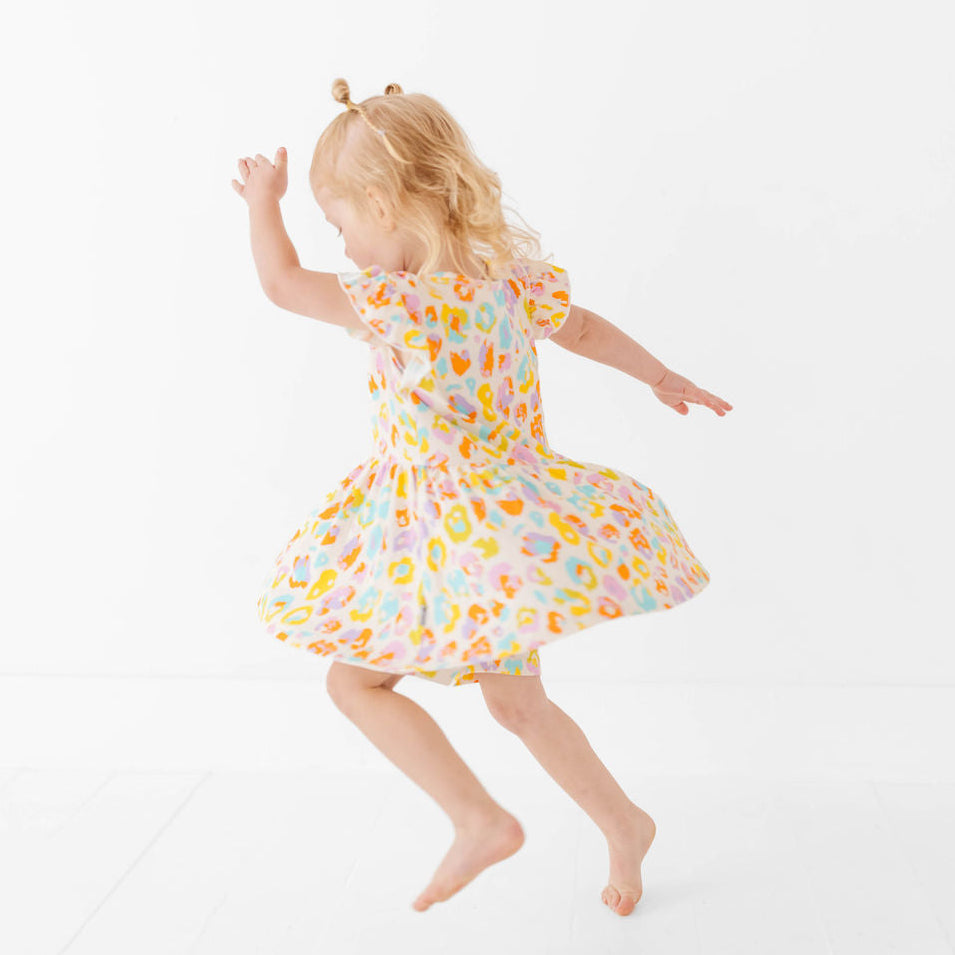 Child wearing a colorful dress with a floral pattern on a white background