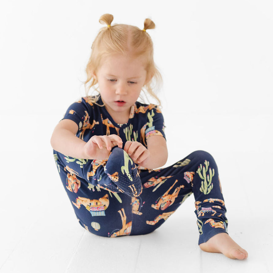 Child wearing a navy blue pajama set with animal prints on a white background