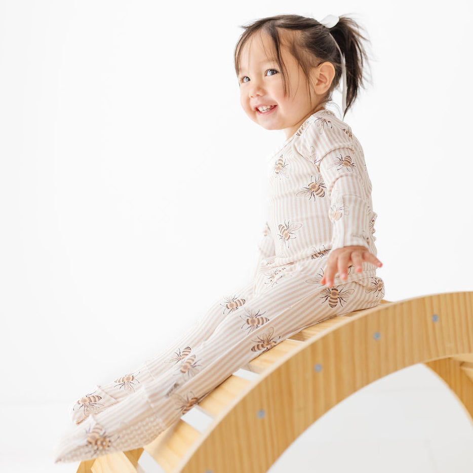 Child sitting on a wooden seesaw against a white background