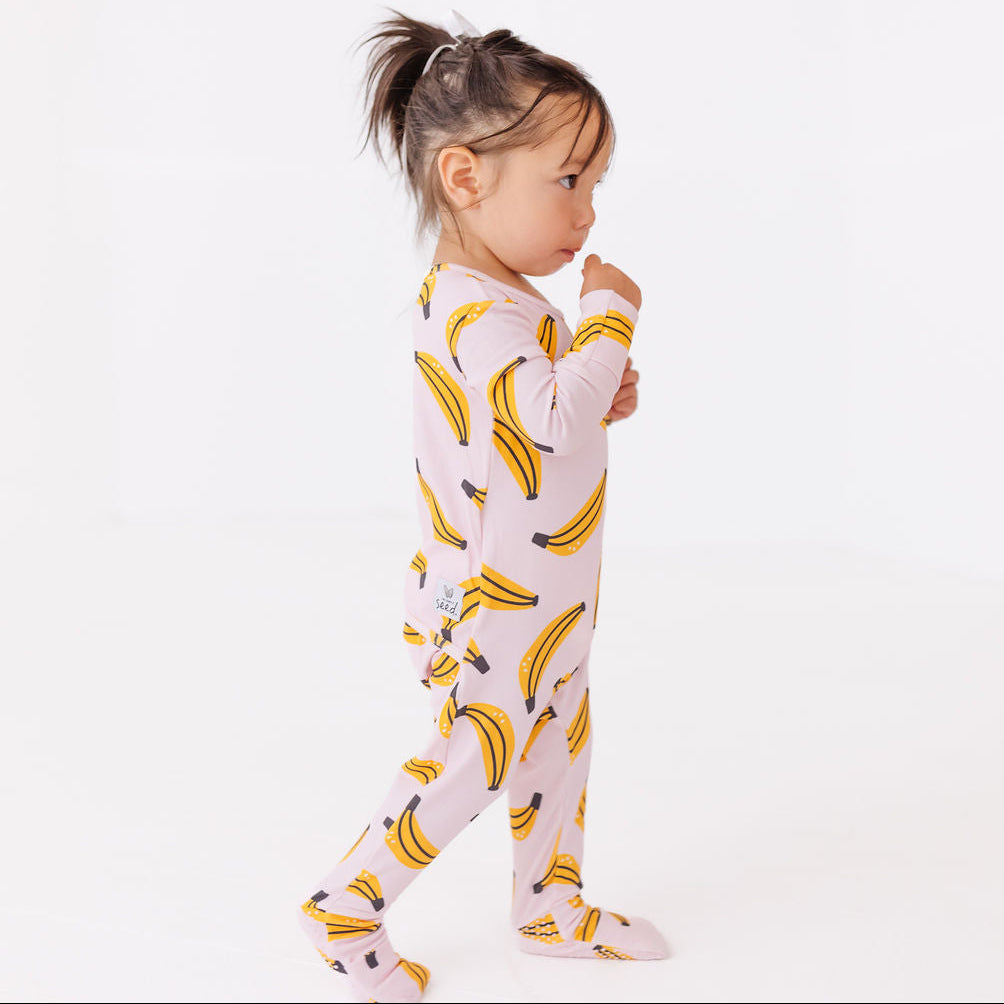 Child wearing a onesie with banana pattern on a white background