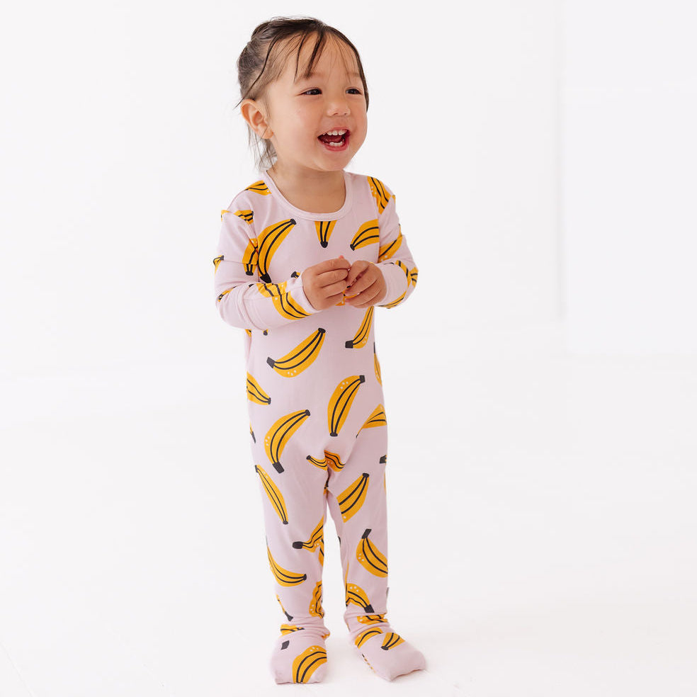 Child wearing a banana-patterned onesie on a white background