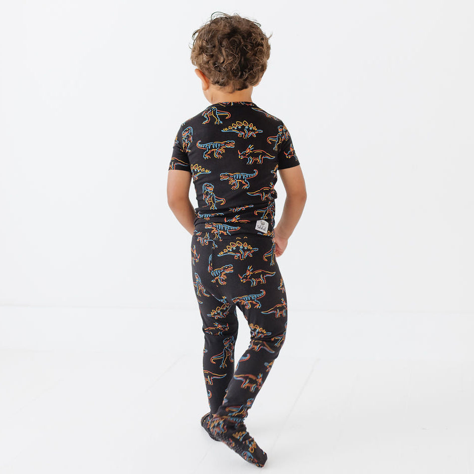 Child wearing a black dinosaur-patterned onesie on a white background