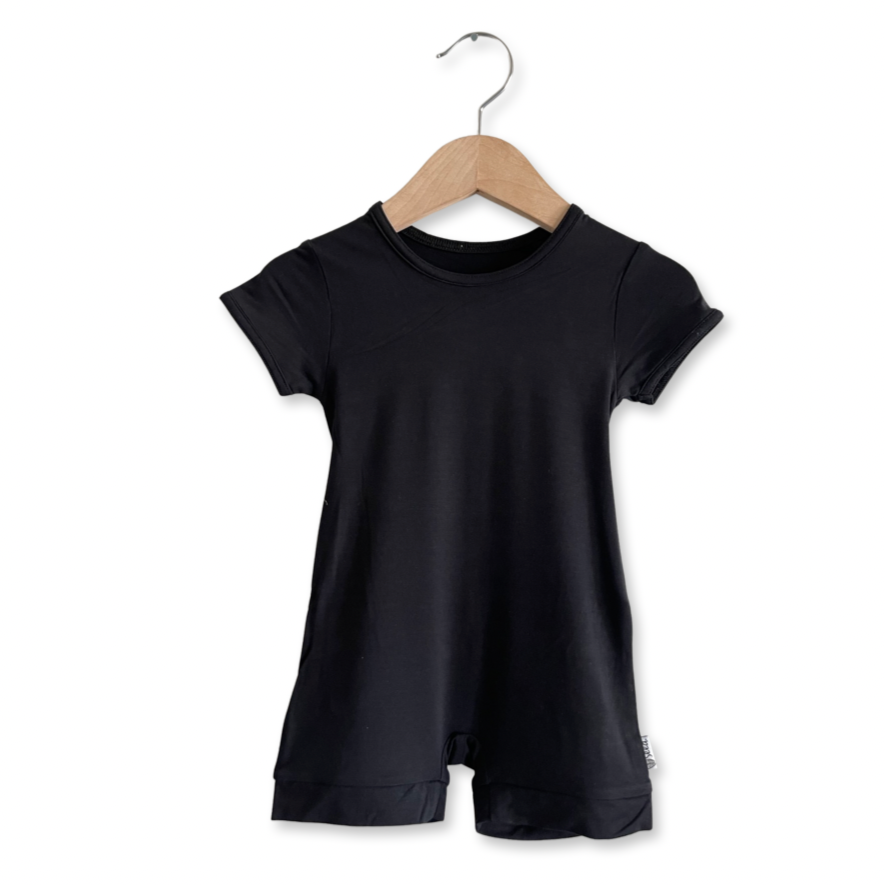 A black shorty romper for babies, displayed on a wooden hanger.