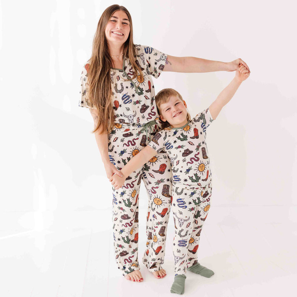 Woman and child wearing matching pajama sets with a cowboy theme on a white background