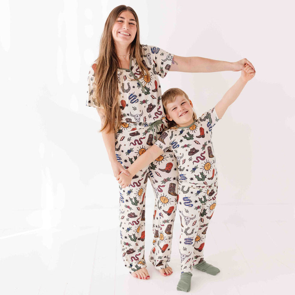Woman and child wearing matching pajama sets with a cowboy theme on a white background