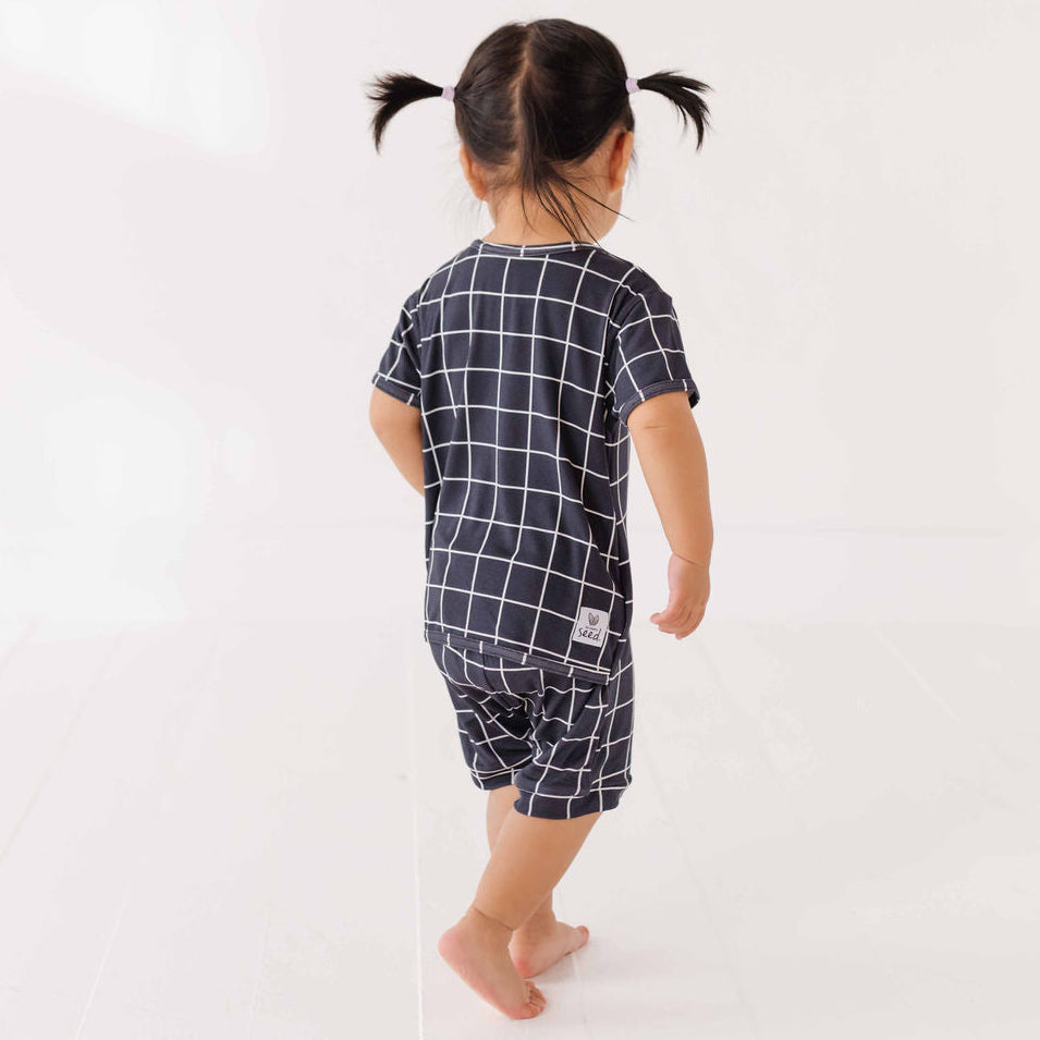 Child wearing a navy blue checkered outfit on a white background