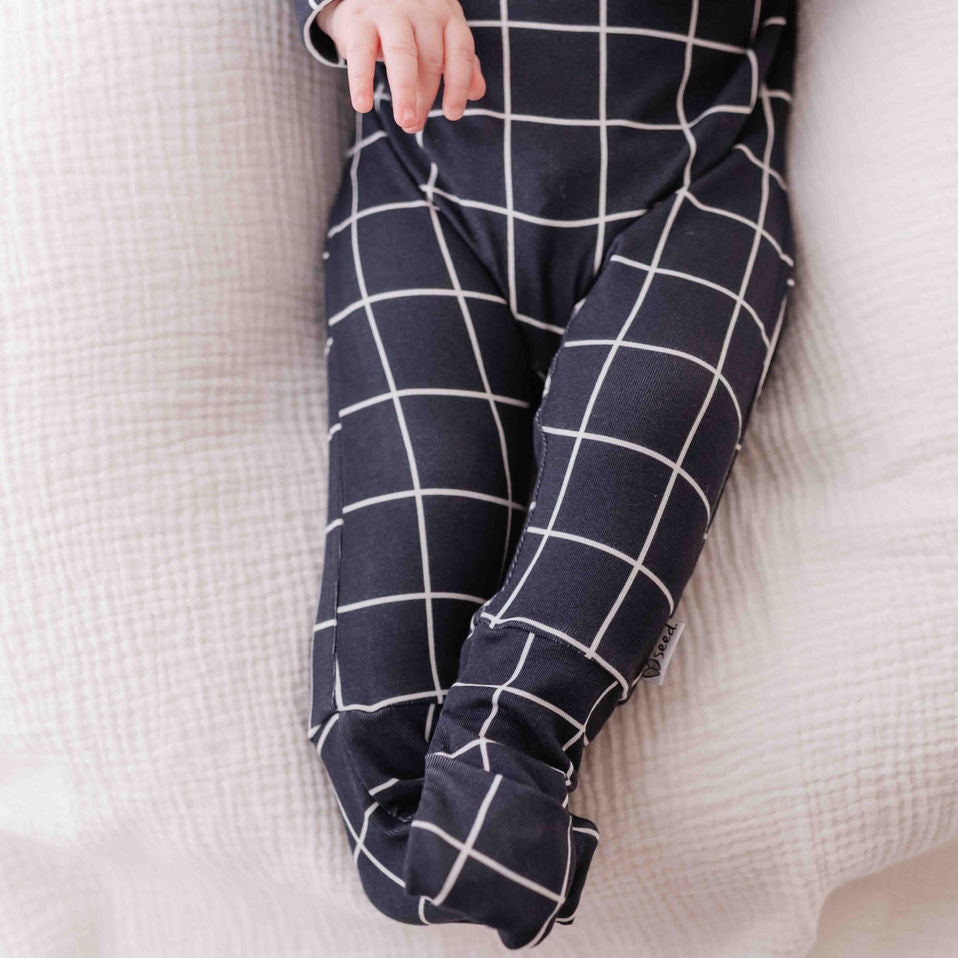 Navy blue grid-patterned pants on a light beige blanket
