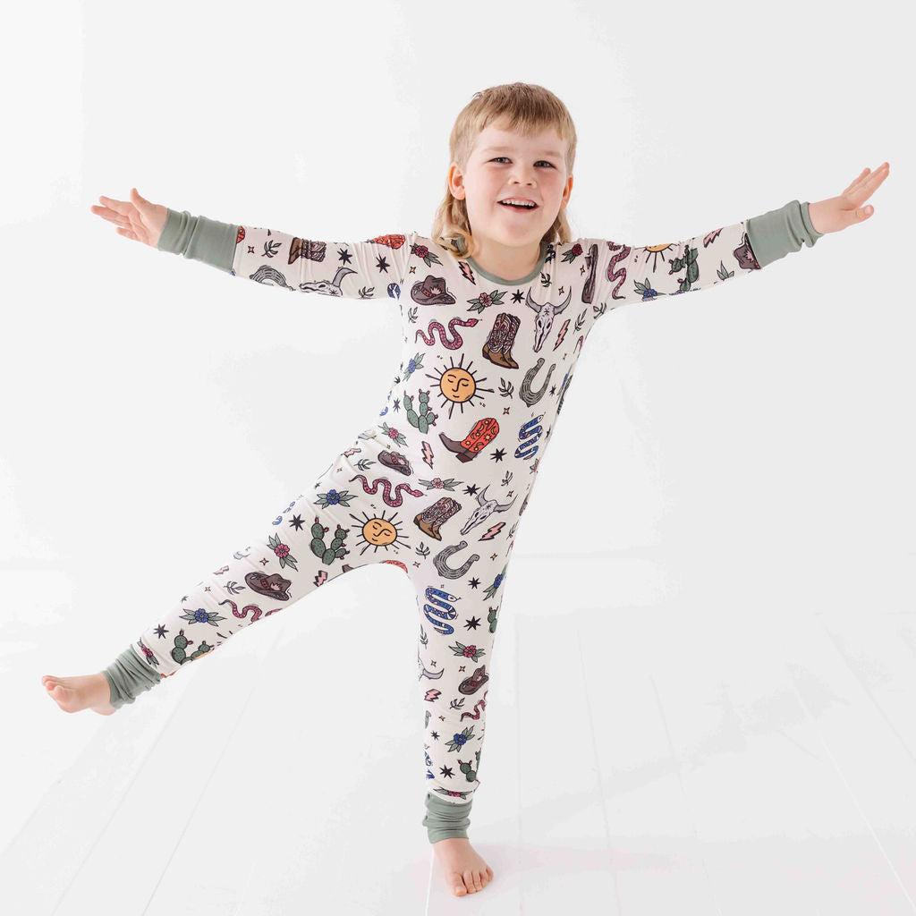 Child wearing a patterned onesie with arms outstretched on a white background