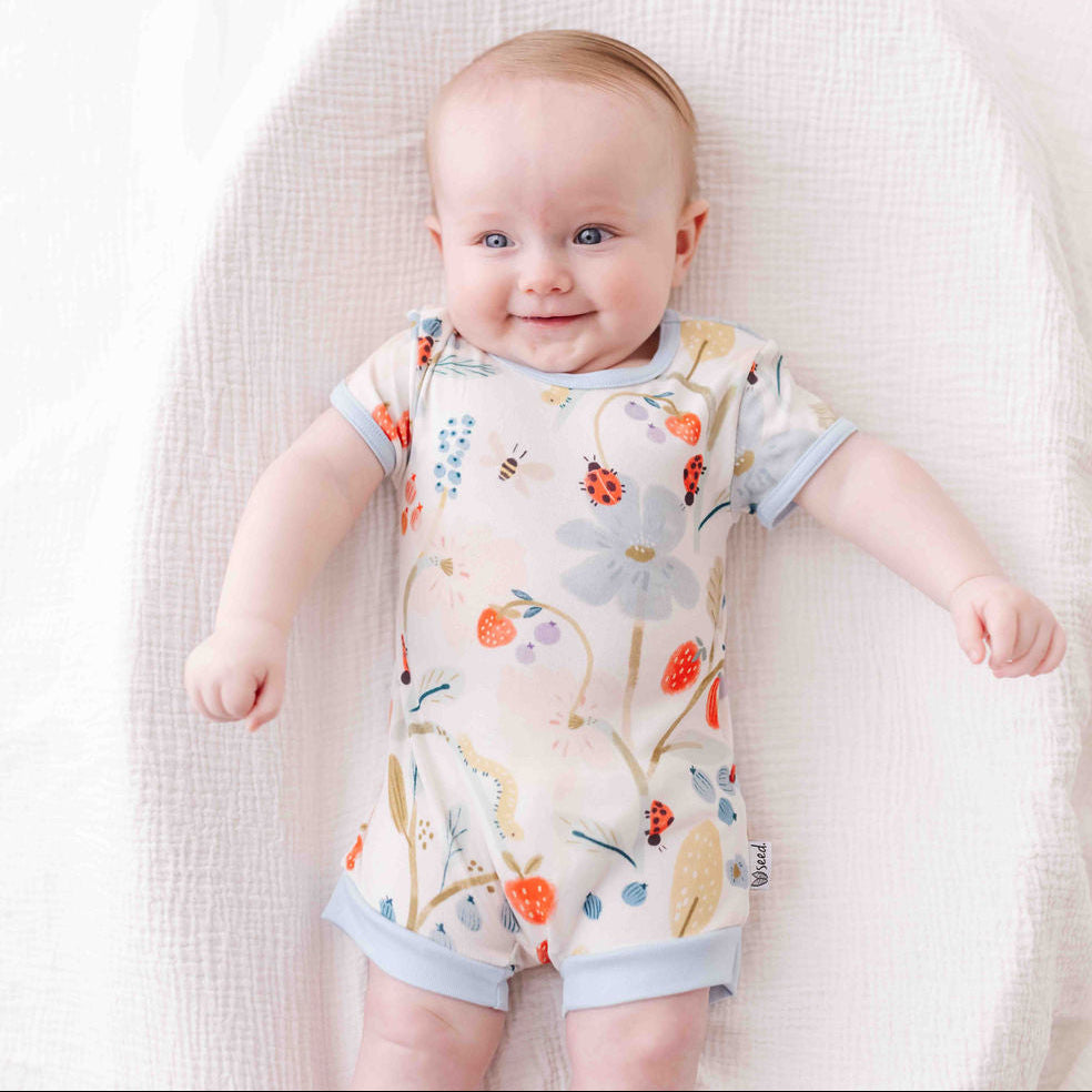 Baby wearing a floral romper on a white blanket
