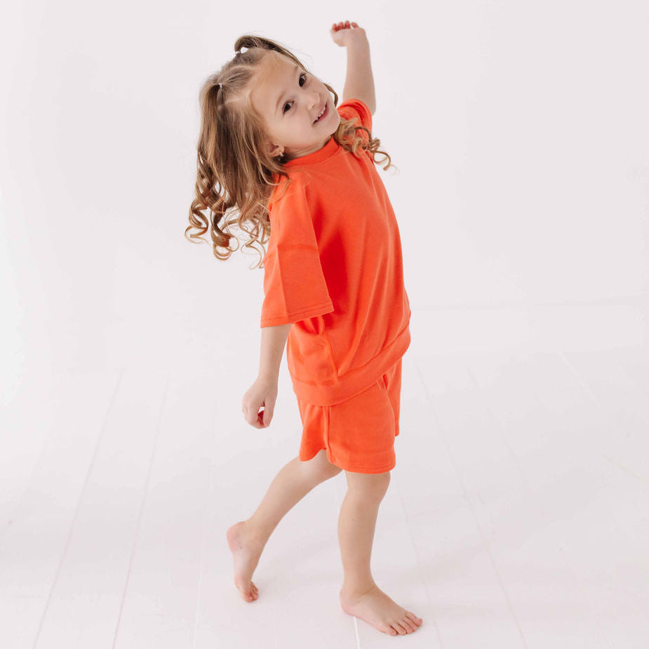 Young girl wearing an orange outfit on a white background