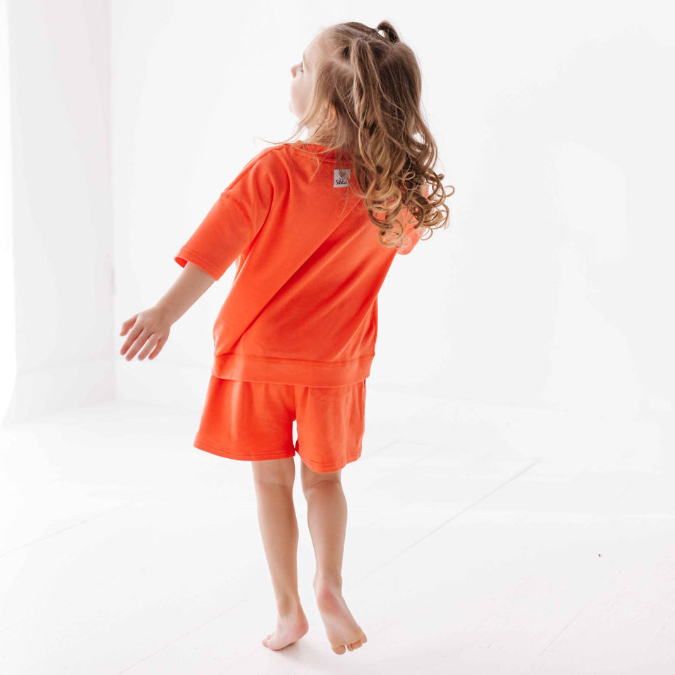 Child wearing an orange outfit on a white background