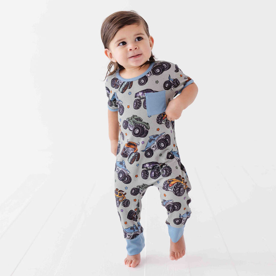 Child wearing a patterned onesie with vehicles on a white background
