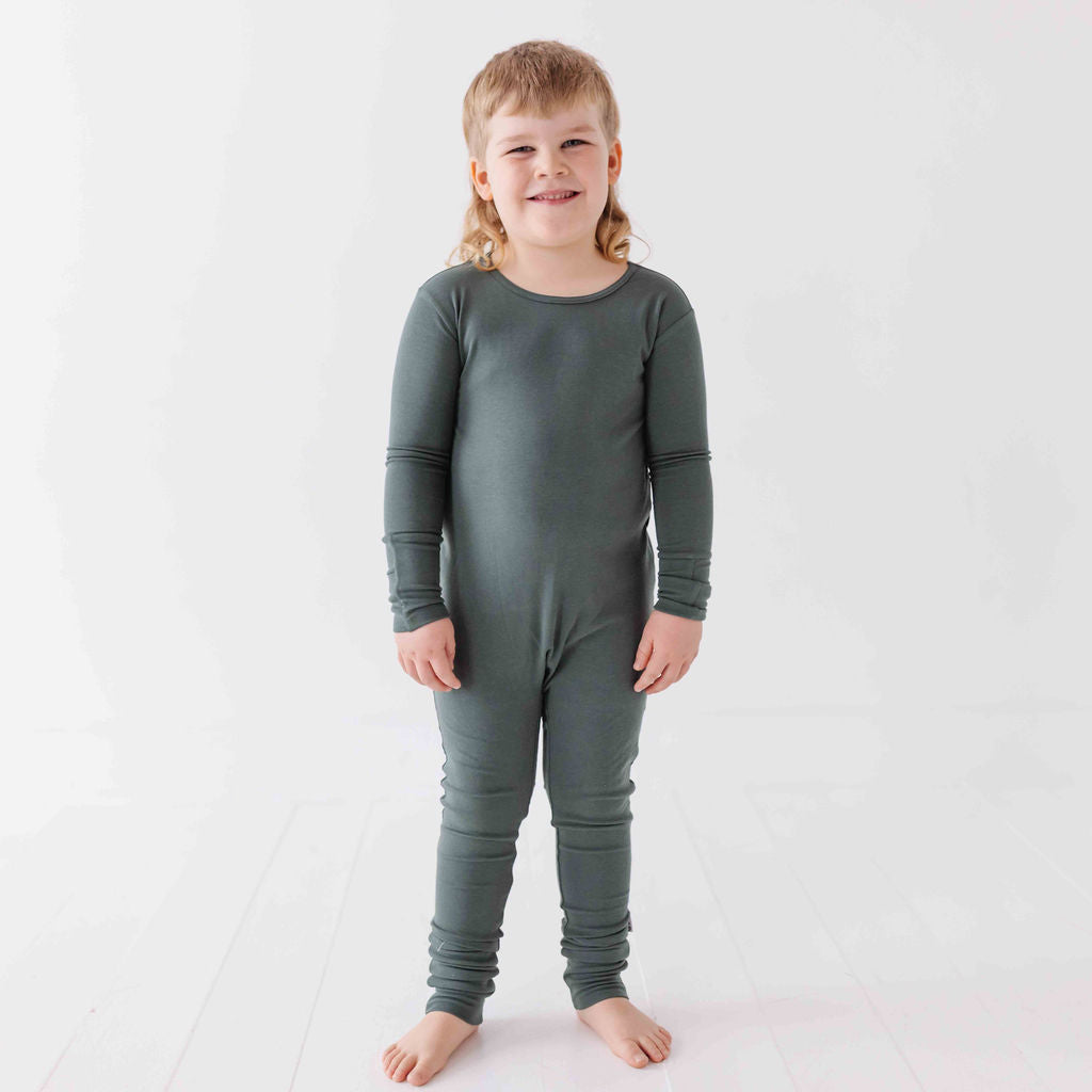 Child wearing a green onesie against a white background