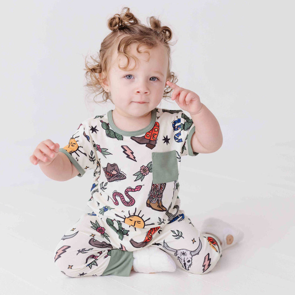 Child wearing a colorful onesie with animal prints on a white background