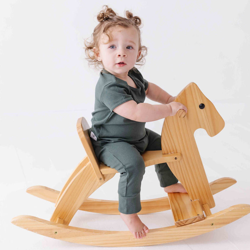 Child sitting on a wooden rocking horse against a white background