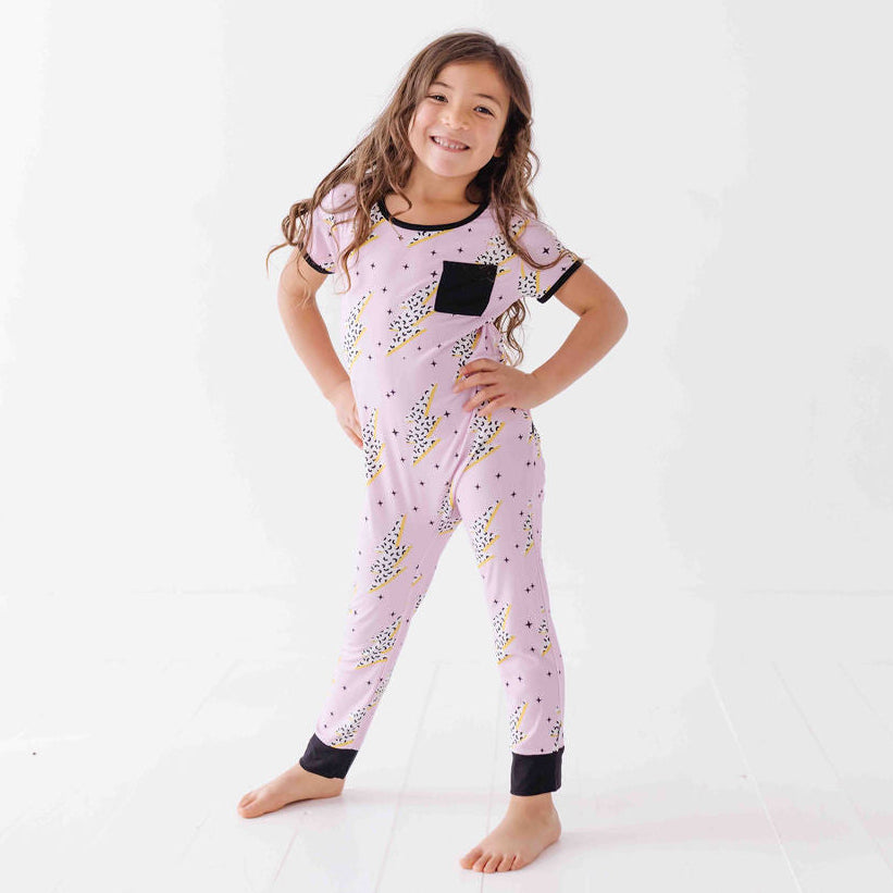 Child wearing a pink onesie with black accents on a white background