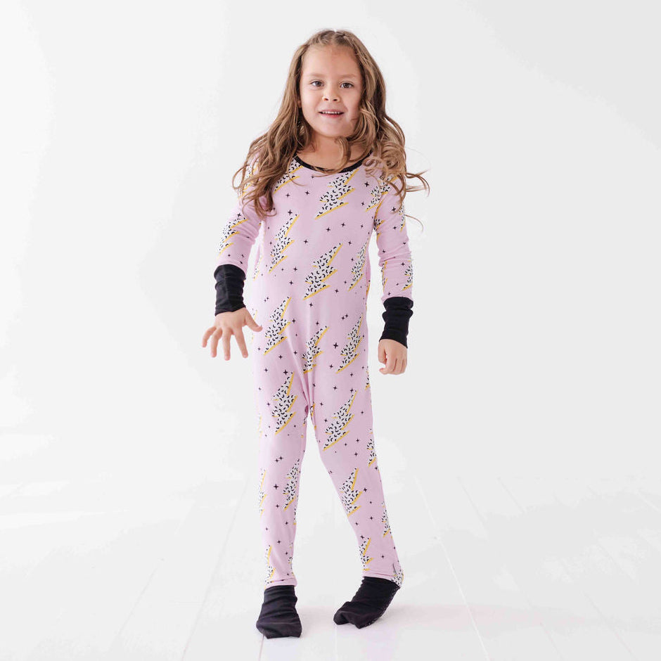 Young girl wearing a pink onesie with animal prints on a white background