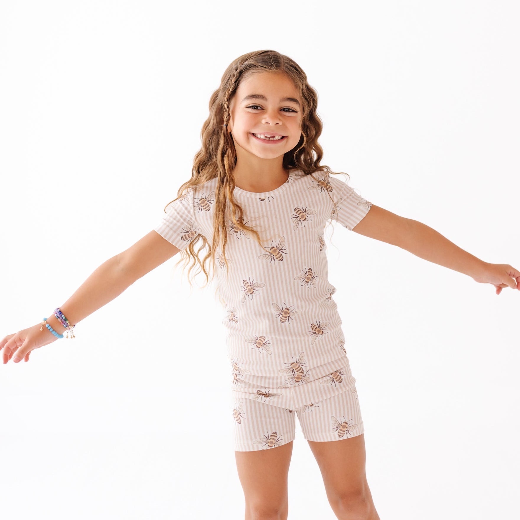 Girl wearing outfit with stripes and bees on a white background 