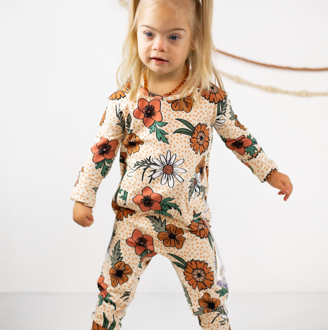 Child wearing a floral onesie on a white background
